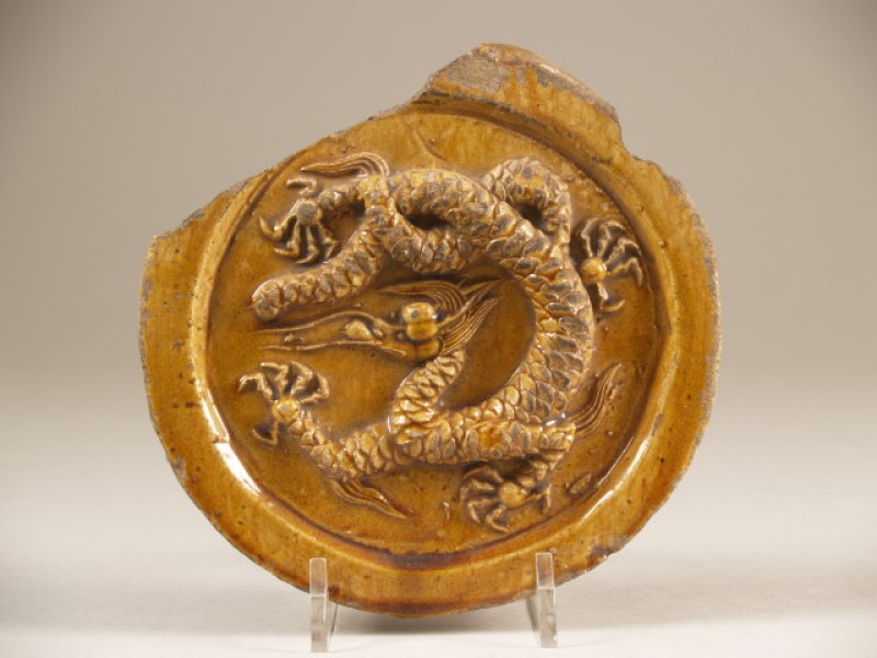 Dakpan, dan wel fragment van een nokdakpan, met decor van draak in reliëf
